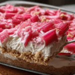 No-Bake Rhubarb Dessert cut into squares showing three layers of graham cracker crust, cream cheese filling, and pink rhubarb topping